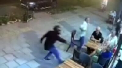Mersin’de kask takarak kaldırımdan yürüyen bir şahıs, tantunicide oturan kişiyi
